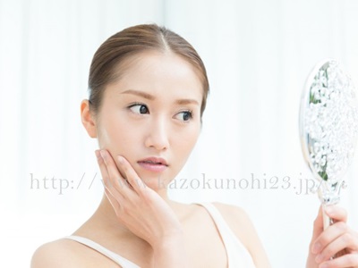 肌質でこんなにも違う！意外と知らない肌質別スキンケア方法画像は、顔に手を当てて、現状の肌具合を鏡で確認している30代女性。